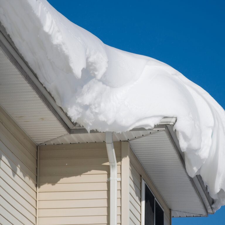 Thick layer of snow covering a residential roof, showcasing the need for proper winter roofing care.